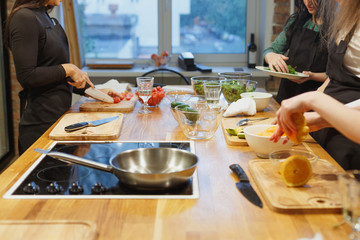 Multiracial funny friends cook some tasteful food at kitchen while drinking wine.