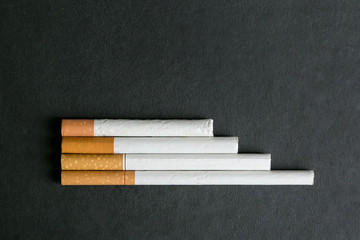 Cigarettes lie on a black background. Several cigarettes stacked neatly on a black background