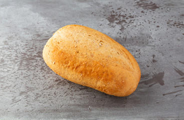 Small loaf of wheat bread atop a gray mottled background