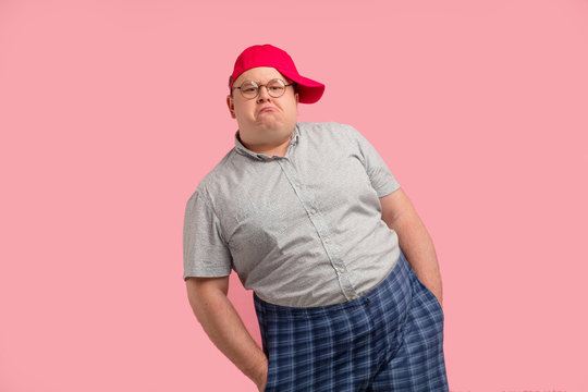 Comical home superhero with arrogant face wearing checkered huge shorts shows his muscles and competence isolated on pink background