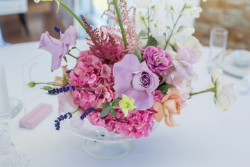 closeup bouquet set of fresh roses, astilbe, carnation, delphinium, eustoma, ornithogalum, lavender and hydrangea decorate table on wedding banquet. Event decoration with fresh flowers