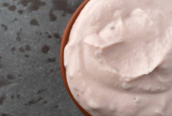 Small bowl of red raspberry yogurt on a gray background top close view