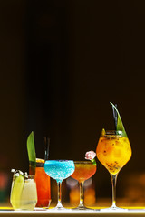 A set of different alcoholic cocktails in glass glasses on the bar counter.