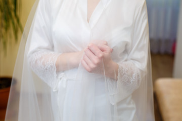 Bride's hands folded on a white wedding dress