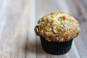 Whole grain muffin on wooden background.