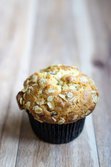 Whole grain muffin on wooden background.