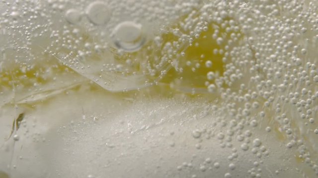 Macro close-up pouring soda water with ice and bubbles. mineral bubbles in glass. 4K UHD video 3840x2160