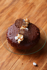 Contemporary Chocolate Peanut Butter Mousse Cake covered with chocolate glaze, on wooden table.