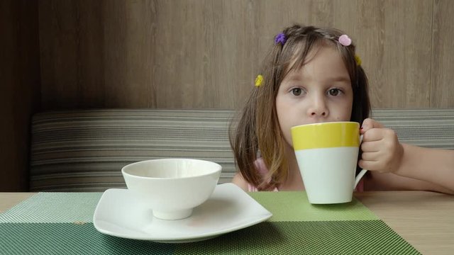 Beautiful cute little child, baby gerl, drink tea. Kid having breakfast.