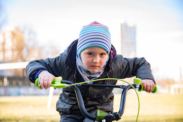 Obraz premium Little child boy on bicycle in park outdoor. A child is riding a children's bike
