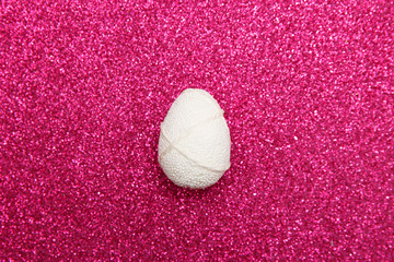 Easter white egg on pink glitter background. Minimal easter concept. Happy Easter card with copy space for text. Top view, flatlay.