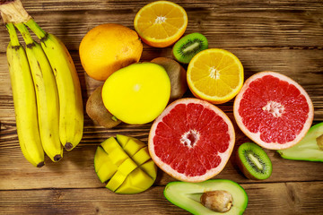 Assortment of tropical fruits on wooden table. Still life with bananas, mango, oranges, avocado, grapefruit and kiwi fruits