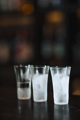 close up of three frost-covered glasses standig in line isolated on dark blurred background.