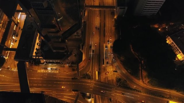 Aerial view of the city at night with modern buildings, highway intersection and moving cars. Stock. Big city nightlife.