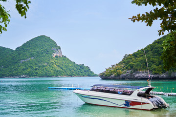 Fototapeta premium White boat on the shore against the backdrop of the pier and mountains