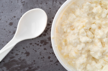 Top close view of a container of pineapple cottage cheese with a spoon to the side on a gray table