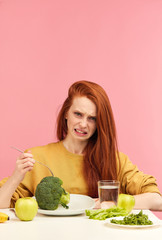 Symptoms of anorexia manifested in disgust to food. Portrait of grimacing unsatisfied facial...