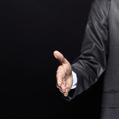 close up.businessman, hand out for a handshake.isolated on black background