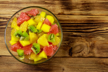 Tasty fruit salad in glass bowl on the wooden table