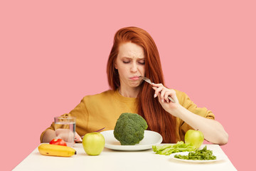 Red-haired woman in bad temper keeping strict vegetarian diet being tired of restrictions and hates...