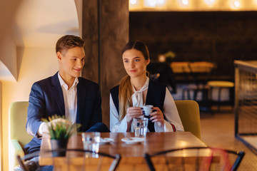 A stylish couple drinks morning coffee at the cafe, young businessmen and freelancers