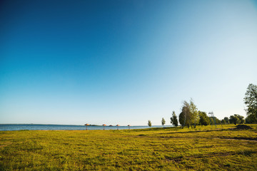 Fototapeta premium Blue sky and green trees over lake. Beautiful summer morning near lake. Water landscape. Summer vacation concept. Travel, lifestyle and nature concept.
