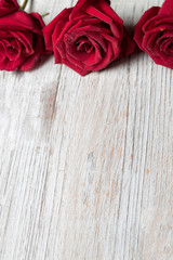 Three Red roses on light wooden background with copy space, top view, vertical composition  - Image