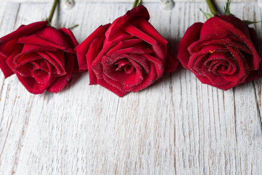 Three Red roses on light wooden background with copy space, top view  - Image