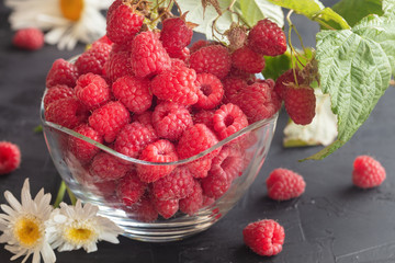 Fresh Deluxe Raspberries in glass bowl with field flowers on dark wooden background. Close up, high resolution product. Harvest Concept - Image