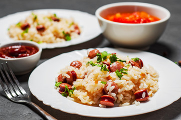 rice with smoked sausage in white plate on Dark grey black slate background