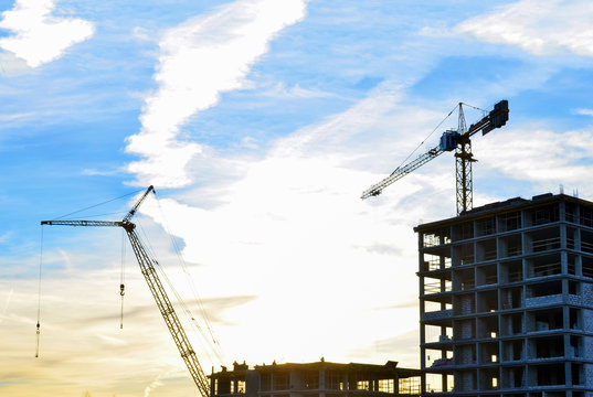 Cranes and construction site on the background of sunset and beautiful sky
