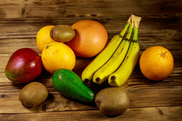 Assortment of tropical fruits on wooden table. Still life with bananas, mango, oranges, avocado, grapefruit and kiwi fruits