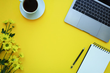 Desk with notebook, pencil, cup of coffee on yellow table. Place for your text