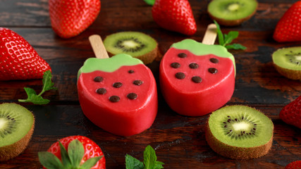 strawberry ice lolly with fresh strawberries and kiwi on wooden table