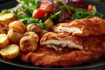 Homemade breaded pork schnitzel with roast potato and vegetables