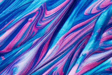 Abstract textured background of pink and blue metallic glitter paint swirls