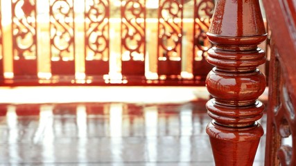 Vintage glossy wooden newel post with flare light and reflection on surface of traditional banister and wooden floor, close up with copy space