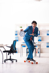 Young handsome businessman with longboard in the office 