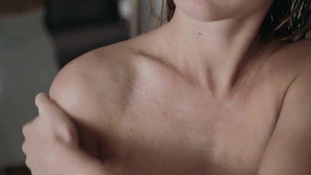 The woman applying lotion on chest and neck after shower