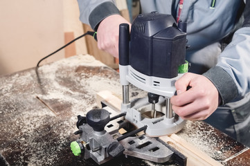 Close-up electric milling cutter in the hands of a worker in a home workshop. Starting a business....