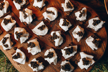 Delicious sandwiches with black caviar and cheese on a wooden Board top view