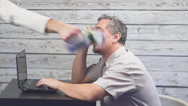 Internet business. The businessman working at the computer. And the money falls on him.