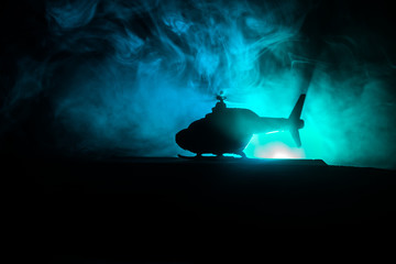 Silhouette of military helicopter ready to fly from conflict zone. Decorated night footage with helicopter starting in desert with foggy toned backlit. Selective focus. © zef art