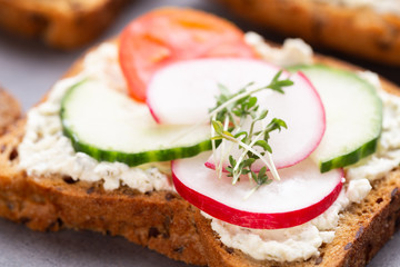 Sandwich with cereals bread and salami on dark marble background.