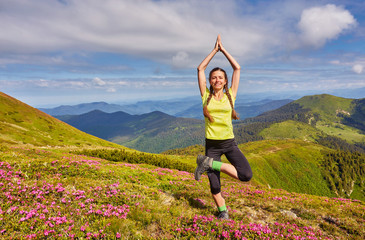 Young girl doing yoga fitness exercise outdoor in beautiful mountains landscape.