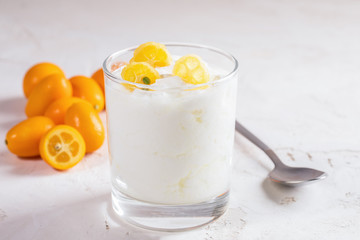 Close-up homemade yogurt with slices of kumquat in glass on white background.