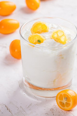 Close-up one transparent glass with  yogurt with slices of exotic kumquat on white background.