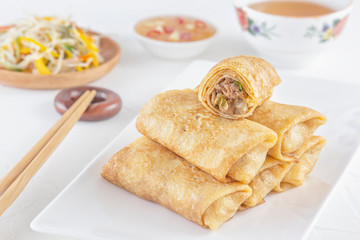 Traditional Chinese tortillas filled - bings in a plate on a white background, salads, Dam Sam snacks and cup of tea. Close-up