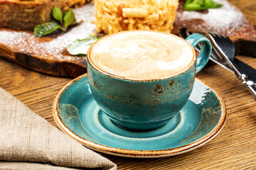 Cappuccino Cup with latte on wooden background. Beautiful foam, green ceramic Cup.