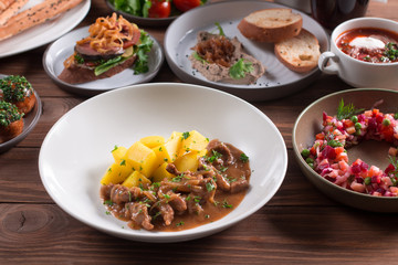 Beef Stroganoff, goulash, with sauce and mushrooms, and boiled potatoes, shot on a dark rustic texture